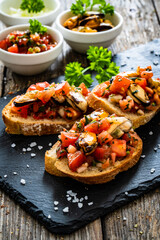 Tasty sandwiches - toasted bread with tomatoes and mussels on wooden table
