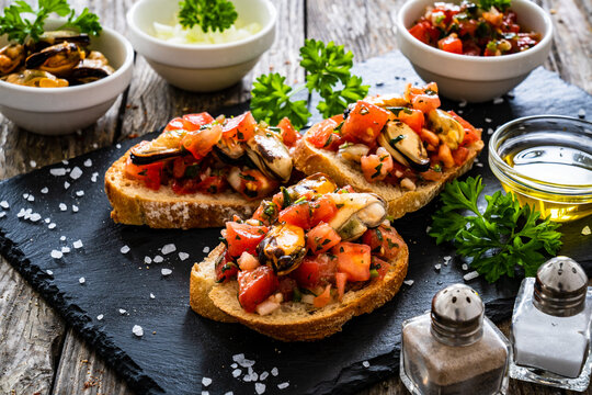 Tasty sandwiches - toasted bread with tomatoes and mussels on wooden table
