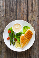 Barbecued chicken breast and green asparagus on wooden table
