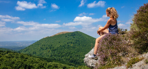 Woman sitting on peak looking at panoramic view of Auvergne mountain- Puy de Dome in France