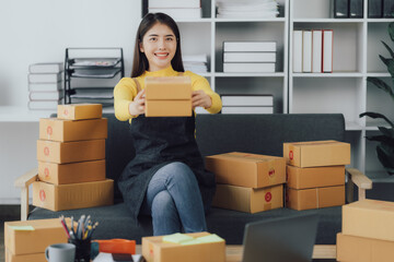 tarting Small business entrepreneur SME freelance,Portrait young woman working at home office, BOX,smartphone,laptop, online, marketing, packaging, delivery, SME, e-commerce concept