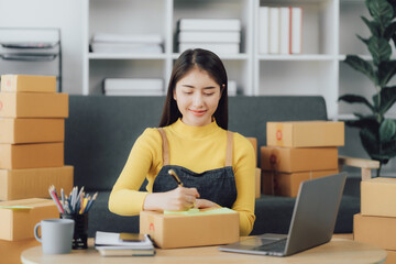Obraz na płótnie Canvas tarting Small business entrepreneur SME freelance,Portrait young woman working at home office, BOX,smartphone,laptop, online, marketing, packaging, delivery, SME, e-commerce concept