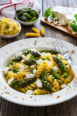 Noodles with asparagus and feta cheese on wooden table
