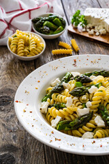 Noodles with asparagus and feta cheese on wooden table
