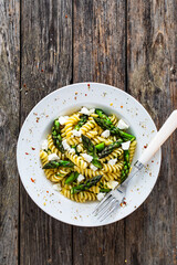 Noodles with asparagus and feta cheese on wooden table
