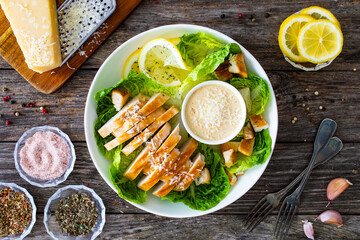 Caesar salad - fried chicken breast and vegetables on wooden table
