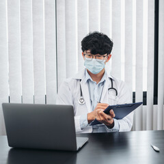 Male doctor in face mask medical using laptop to searching infor