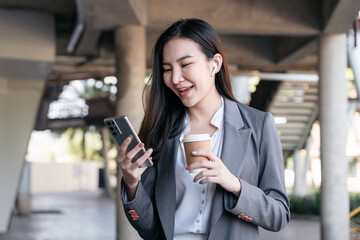 Asian businesswoman in suit, holding coffee cup to drinking and