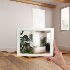 Augmented reality concept. Hand holding tablet with AR application used to simulate furniture and design products in empty wooden interior, urban jungle bathroom