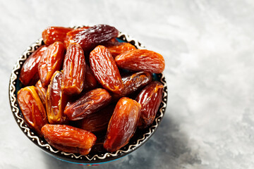Dried dates in bowl on a gray background. Bowl of pitted dates on concrete. Food for Ramadan. Top view. Copy space
