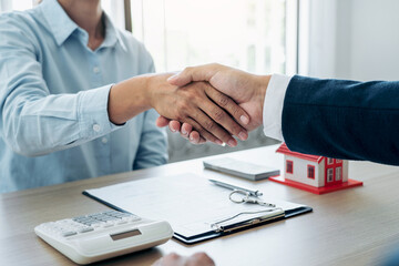Estate agent and customers shake hands together celebrating the