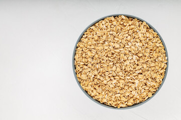 Oat flakes bowl on a white background. Raw oatmeal for a healthy breakfast. Copy space. Top view