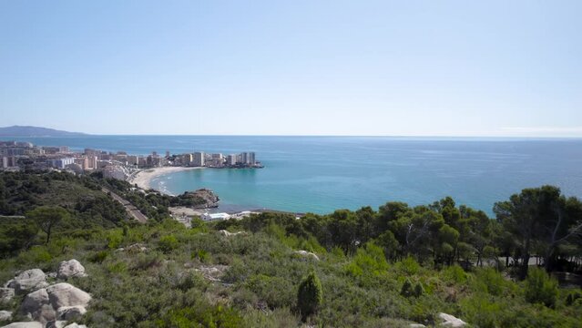 Slow 4K aerial view towards Oropesa sport port over the hill vegetation on a sunny day