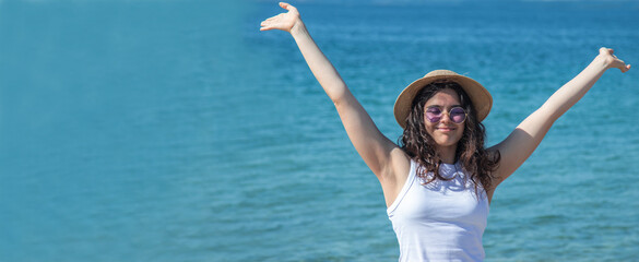 relaxed free young girl with arms raised on sea background