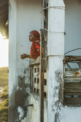 African woman looks out from an old balcony in Accra Ghana West Africa