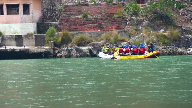 wide shot of yellow raft with people enjoying adventure sports floating on the green waters of the ganga in rishikesh haridwar for this popular summer adventure sport
