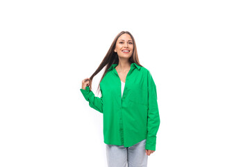 smiling happy young european female model with well-groomed black hair and make-up dressed in a green shirt on a white background with copy space