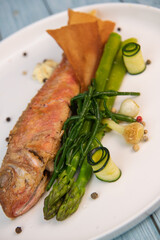 Plate of fried small fish red mullet with green asparagus. High quality photo