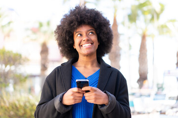 African American girl at outdoors using mobile phone and looking up