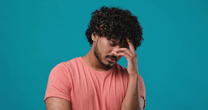 Serious pensive thinkful indian man standing isolated over blue studio background