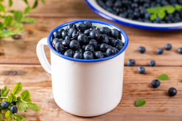 Fototapeta na wymiar Fresh raw organic farm blueberry in white cup on wooden table