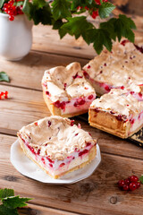 Pieces of sweet homemade currant pie on a plate with red currant on wooden table