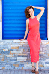 Stylish woman in red dress standing near blue shutters