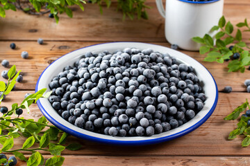 Metal bowl with frozen blueberries on wooden table. Frozen berries.
