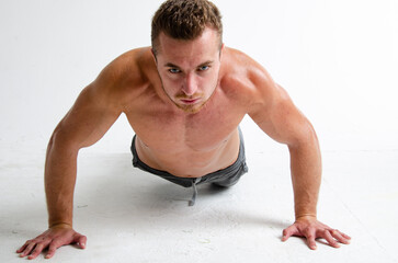 A young handsome guy does exercises on the abdominal muscles. A man with a beautiful athletic body.