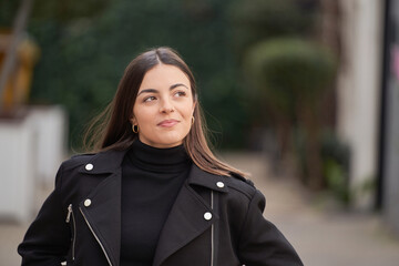 Fototapeta premium portrait of smiling brunette woman with pensive face in the city