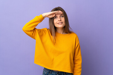 Young Slovak woman isolated on purple background looking far away with hand to look something