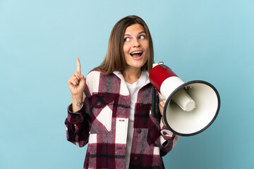 Young Slovak woman isolated on blue background holding a megaphone and intending to realizes the...
