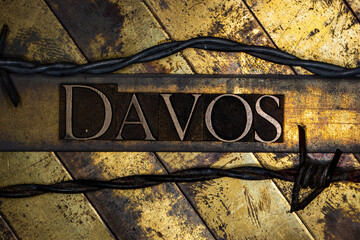 Davos text with barbed wire on grunge textured copper and gold background