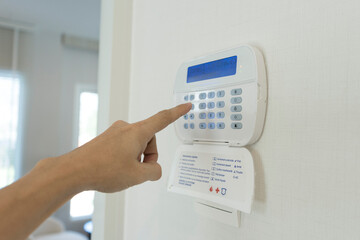 A person hand programing a home security alarm.