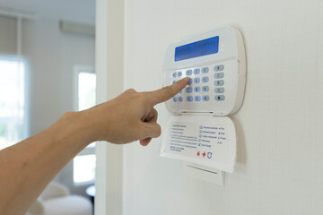 A person hand programing a home security alarm.