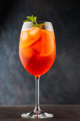 Aperol Spritz cocktail in glass with orange and fresh mint on dark background. Traditional italian aperitif cocktail