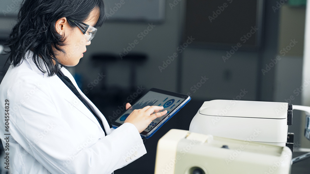 Poster a researcher using experimental equipment while looking at a tablet screen. research and development