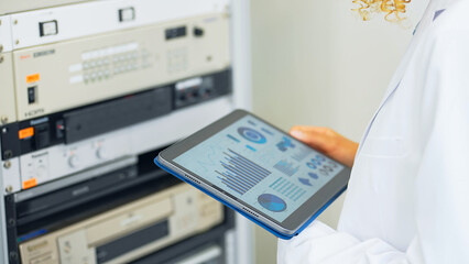 Engineer holding a tablet and operating an electronic device.