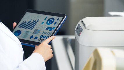 タブレット画面を見ながら実験機器を使う研究者