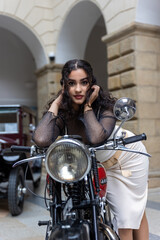 Sexy girl with long black hair is posing by  historic motorcycle. Vertically