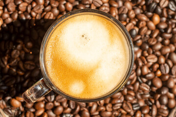 Crema of black coffee in a clear glass on a coffee beans background, selective focus, soft focus.