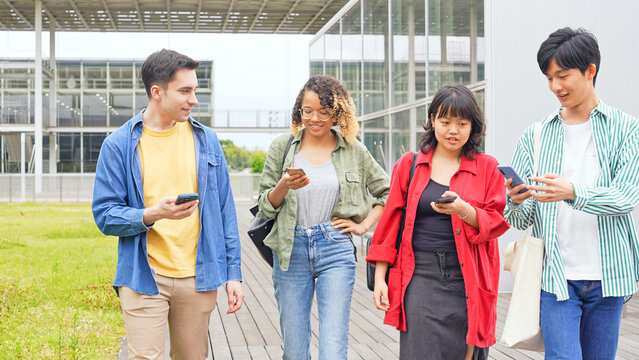 Multinational youth group walking with smart phone in college campus. College students.