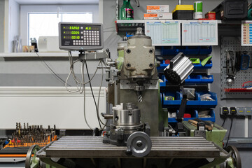  Milling machine. Workshop, CNC milling machine in the foreground, various tools around. High...