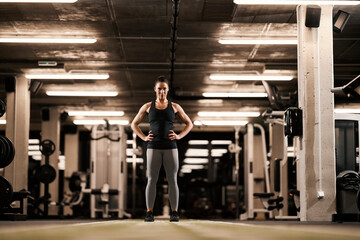 Naklejka na ściany i meble Confident muscular sportswoman is standing in a gym.