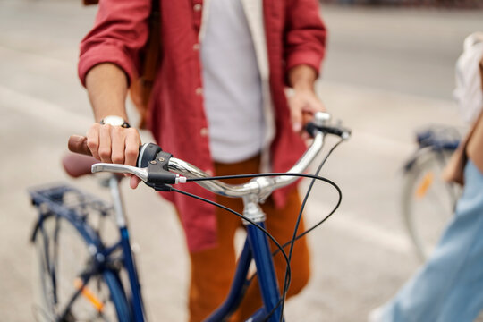 Close up of male's hands holding handles and pushing bicycle on a city street.
