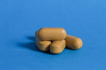 Fototapeta na wymiar Brown pills on a blue background. Close-up