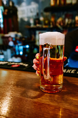 woman bartender's hand hold full glass of beer in a bar