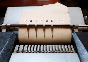 Old vintage machine with words OUTSOURCE, concept of business getting work done by making a...