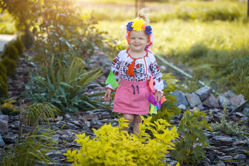 cheerful little girl in national Ukrainian clothes in a sunny summer garden
