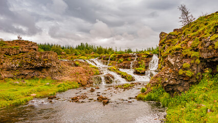 Wonderful waterfal named Kermoafoss in Iceland, in the city park of Reykjavik, in Autumn colors and dramatic sky